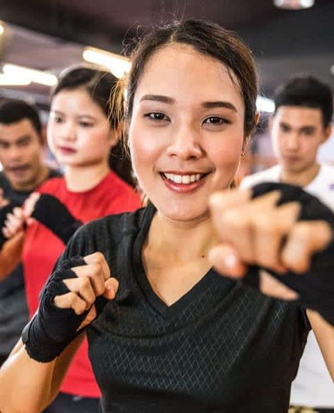 A smiling woman in hand wraps in a fitness class
